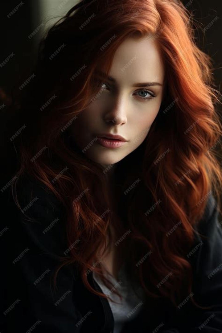 a woman with long red hair is taking a selfie